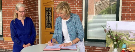 Annette van Velde (dagelijks bestuurslid waterschap Noorderzijlvest) en Karin Hunziker (directeur Meerschap Paterswolde) ondertekenen de overeenkomst aan een hoge tafel.
