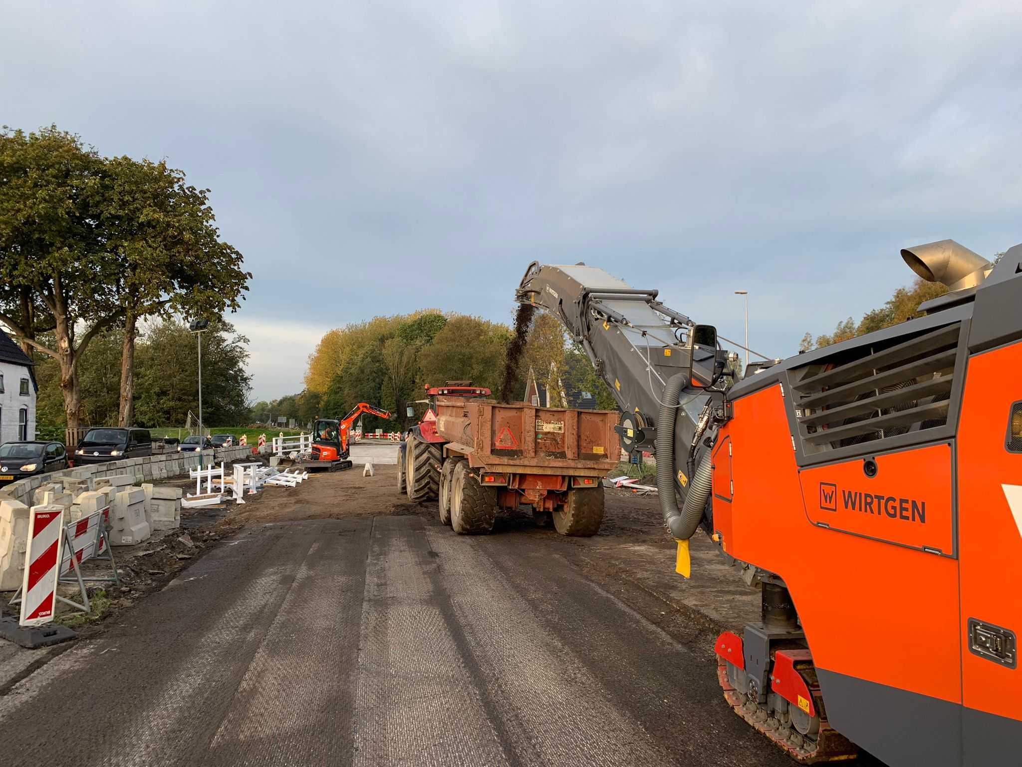 Meerdere machines aan het werk op een opengebroken weg.