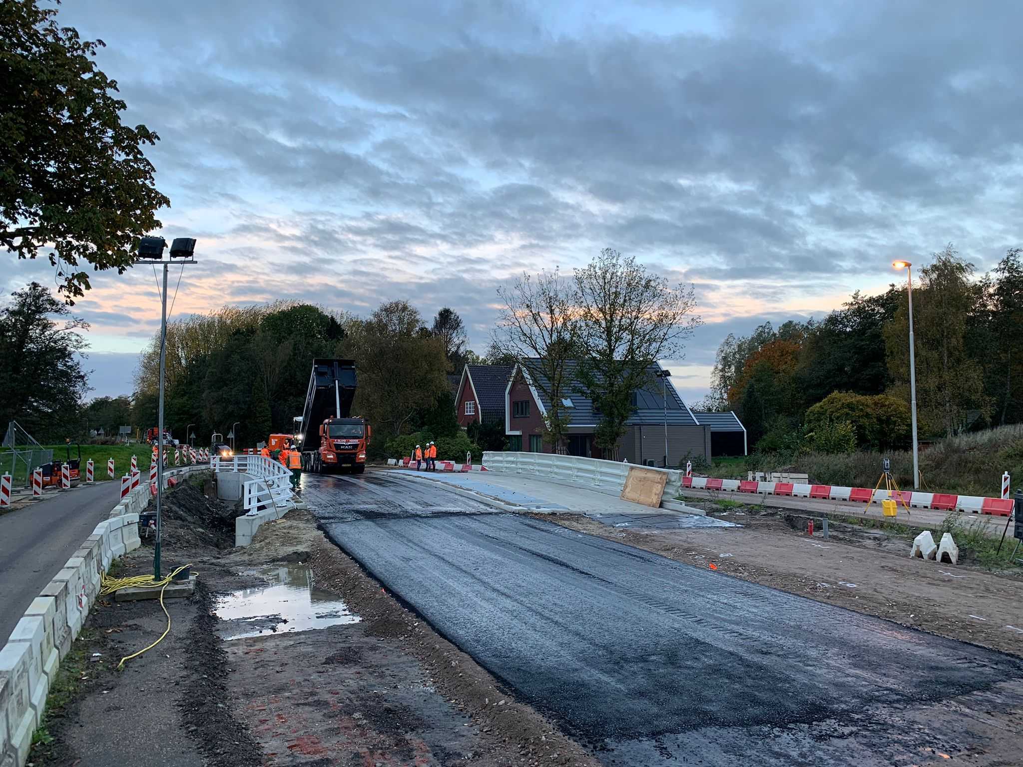 Met schemer wordt op een brug gewerkt en wordt asfalt aangebracht.