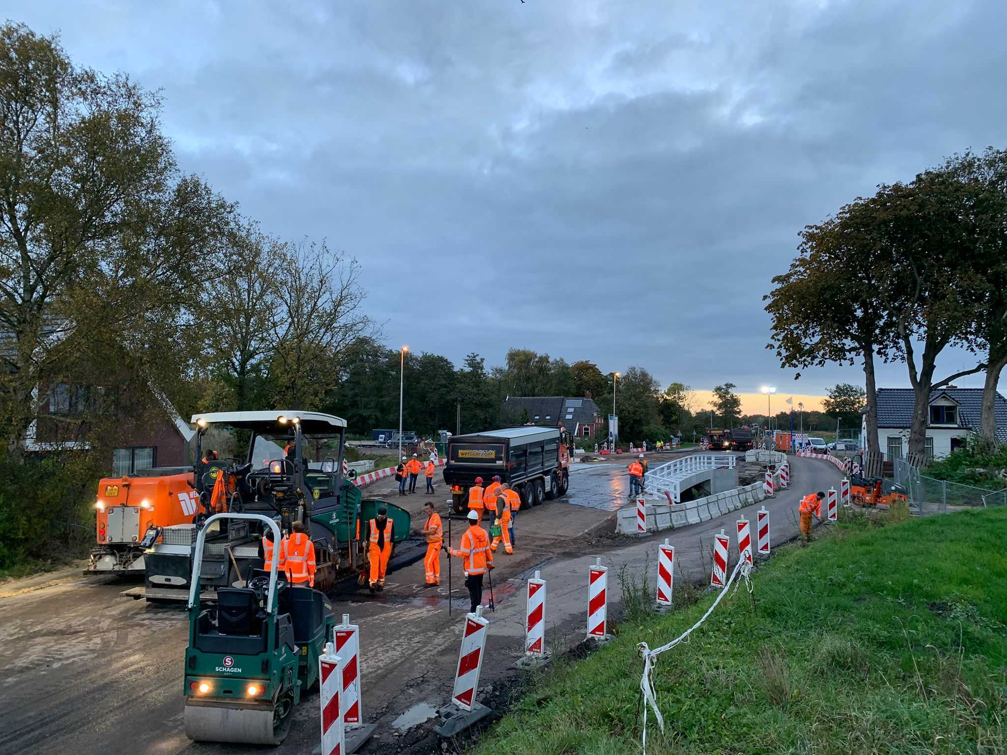 Met schemer wordt op een brug gewerkt en wordt nieuw asfalt aangebracht.