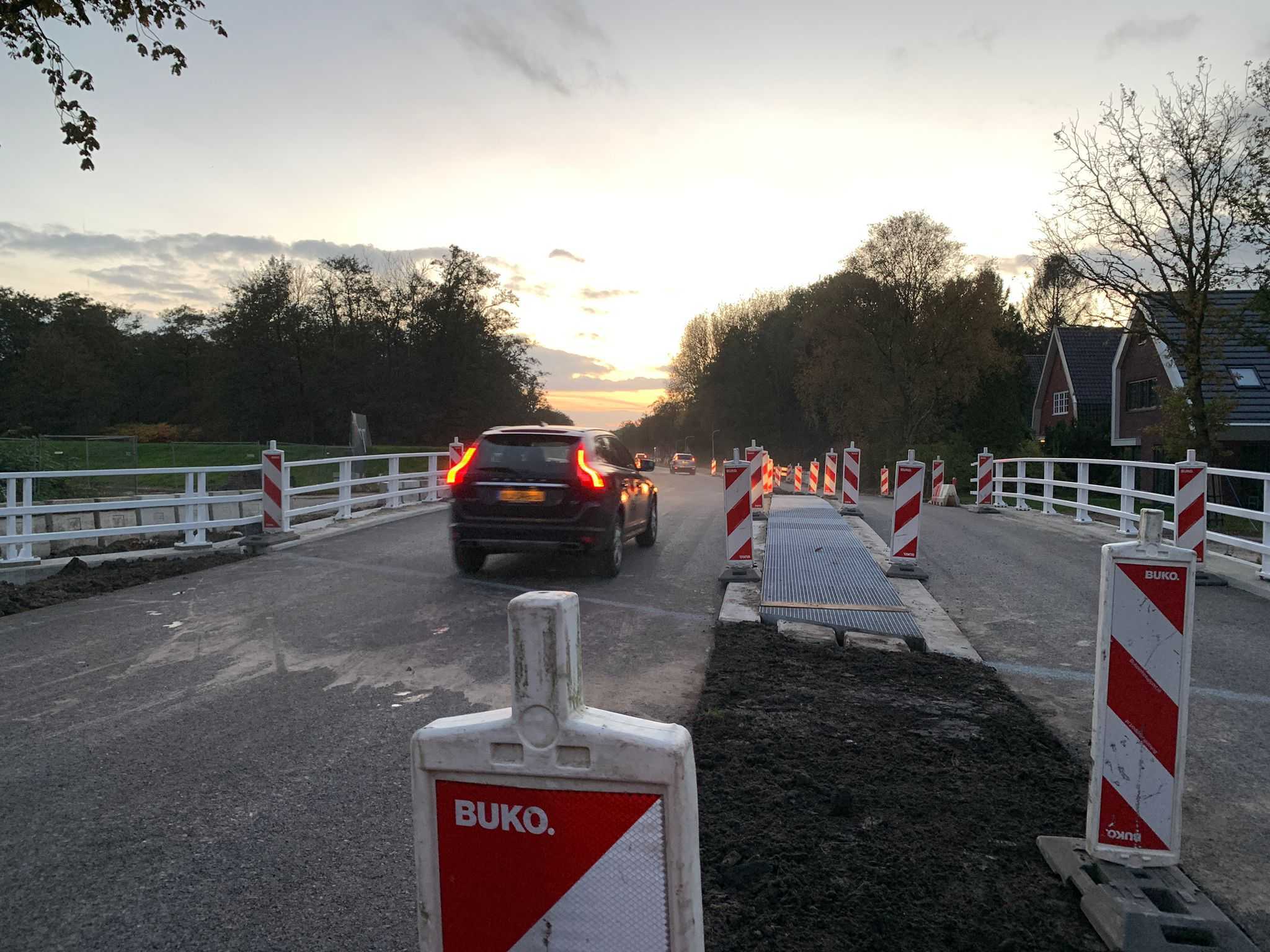 Met schemer rijdt een auto over de brug.