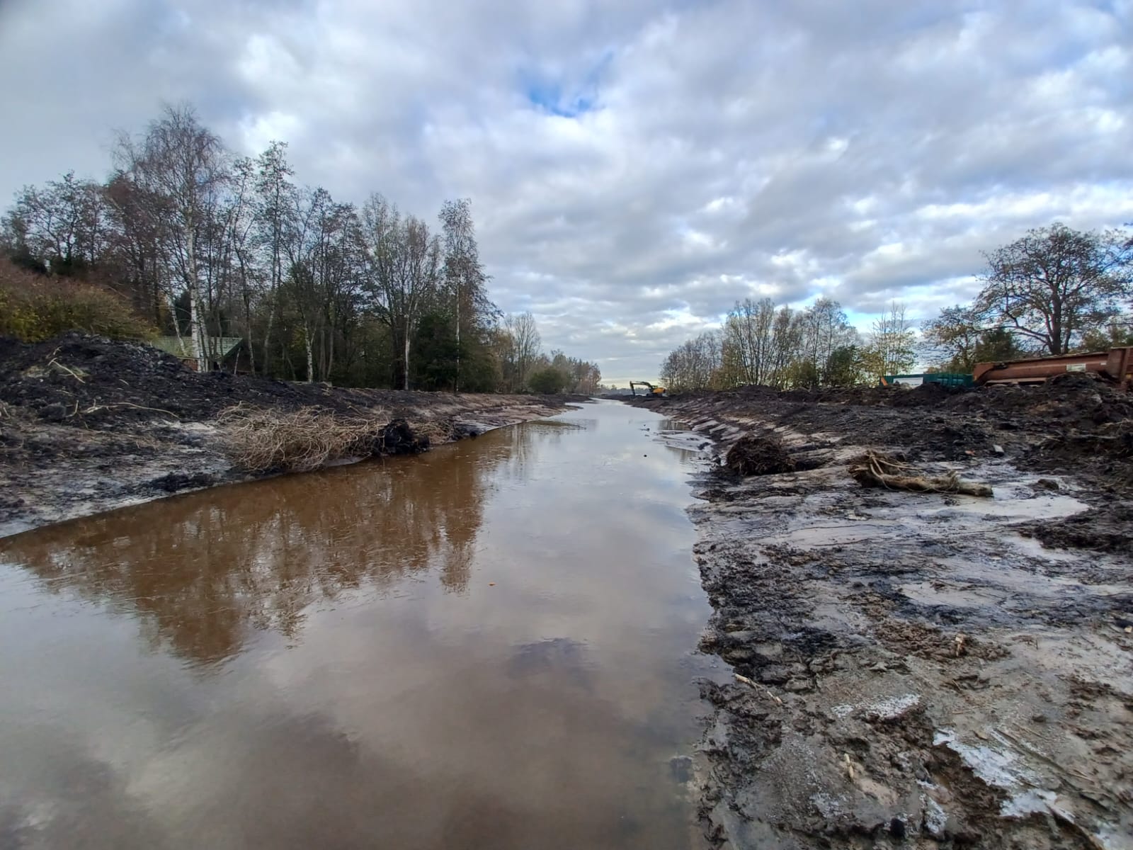 Een slenk met bomen in de achtergrond en een donkere lucht