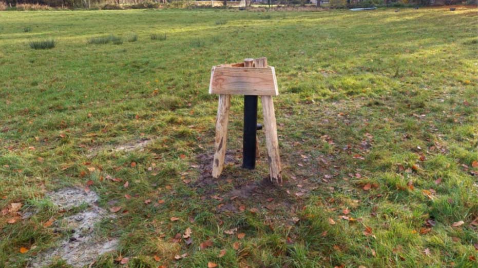 Zwarte peilbuis geplaatst in het veld met hekwerk er omheen